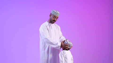 مفهوم بر الوالدين وتقديرهم، تصوير لرجل عربي خليجي عماني يرتدي الدشداشة والكمه يقوم بمعايدة ابنه في العيد، مشاعر الحب والمودة والأبوة، مفهوم بر الوالدين وتقديرهم، ارتداء الملابس العمانية التقليدية في الأعياد الإسلامية، خلفية ملونة