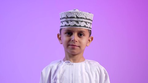 الرجولة والثقة بالنفس، التقاط الصور الشخصية للوثائق الرسمية، الاهتمام بالأناقة والمظهر الخارجي، تصوير لولد عربي خليجي عماني مبتسم يرتدي الدشداشة و الكمه ينظر الى الكاميرا بإيماءات السرور والسعادة