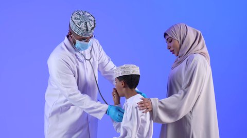 مراجعة وتشخيص حالة المريض ، مهن ووظائف طبية ، تصوير لأم خليجية عمانيه مع طفلها الصغير في زيارة الى دكتور الأطفال ، موعد مع الطبيب لتلقي العلاج ، إستخدام جهاز التابلت ، مفهوم الطب والرعاية الصحية ، الفحص الطبي للأطفال ، تقديم الرعاية والخدمات الصحية