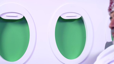 الاستمتاع وممارسه الهوايات المفضله ، الترفيه والتسليه وقضاء الاوقات داخل الطائره, الاستمتاع بقراءه القصص والروايات,  تصوير مقرب من الجانب لرجل عربي خليجي عماني يرتدي الزي العماني يجلس على كراسي الطائره في رحله جويه يقرأ الرجل كتابا