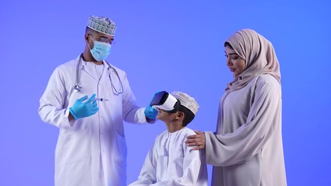 مفهوم التقنيات الإلكترونية الحديثة، حركة اصبع واشارات ، تصوير لطفل خليجي عماني يرتدي نظارات الواقع الإفتراضي (في آر) ثلاثية الأبعاد ويقوم بإيماءات يد مختلفة، يشير بإصبعه السبابة، النقر والضغط، إستخدام حاسة اللمس