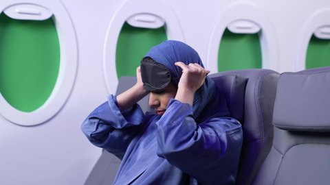 الاستمتاع باجازه الصيف ، قضاء الاوقات الممتعه، تصوير مقرب لامراة عربيه خليجيه اماراتية ترتدي العباءة الزرقاء تقوم بارتداء قناع النوم داخل الطائرة ، الاحساس بالخمول والحاجه الى النوم، رحلة سياحية من خلال خطوط الطيران العماني