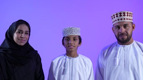 السلام والتهنئة بقدوم العيد, النظر الى الكاميرا بايماءات السعادة ، إظهار مشاعر المودة والمحبة العائلية,  أجواء البهجة والسعادة والاحتفال, تصوير لعائلة عربية خليجية عمانية تحتفل بالأعياد الاسلامية