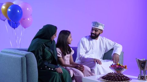 الزيارات العائلية والاحتفال بالأعياد الإسلامية، تقديم الضيافة العربية والحلويات الشعبية، تصوير لعائلة عربية خليجية عمانية تقوم بتبادل المعايدات, إظهار مشاعر الفرح والسعادة بقدوم العيد، مفهوم الحنان والمحبة والمودة