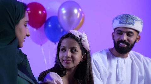 الزينة والبلالين والاحتفالات، تجمع العائلة العمانية لاستقبال العيد المبارك, إظهار مشاعر الفرح والسعادة بقدوم العيد، تصوير لعائلة عربية خليجية عمانية تجلس في غرفة المعيشة بايماءات السعادة ، تبادل المعايدات والتهاني , مفهوم الحنان والمحبة والمودة