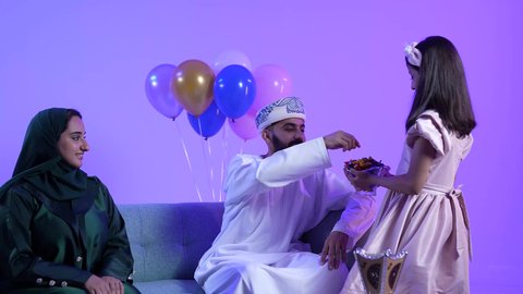 ارتداء الأزياء العمانية التقليدية، توزيع الحلويات الشعبية في الأعياد، تصوير لعائلة عربية خليجية عمانية تحتفل بالعيد المبارك، مفهوم الكرم وتقديم الضيافة العربية ، جو البهجة والفرح والزينة، طقوس الاحتفالات والمناسبات السعيدة في سلطنة عمان