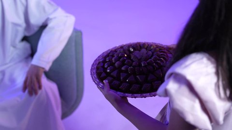 تصوير لعائلة عربية خليجية عمانية تحتفل بالعيد المبارك، مفهوم الكرم وتقديم الضيافة العربية ، ارتداء الأزياء العمانية التقليدية،جو البهجة والفرح والزينة، توزيع الحلويات الشعبية في الأعياد، طقوس الاحتفالات والمناسبات السعيدة في سلطنة عمان