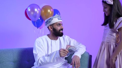 جو البهجة والفرح والزينة ، تقديم العيديات للاطفال فى العيد ، المعايدات والتهنئات وطقوس المناسبات الاسلامية في سلطنة عمان، ارتداء الأزياء العمانية التقليدية، تصوير لعائلة عربية خليجية عمانية تحتفل بالعيد المبارك