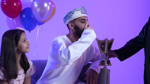 تعابير الحنان والمحبة والمودة ، مفهوم التطيب بالبخور ، تجمع العائلة العمانية لاستقبال العيد المبارك, إظهار مشاعر الفرح والسعادة بقدوم العيد، تصوير لعائلة عربية خليجية عمانية تجلس في غرفة المعيشة بايماءات السعادة