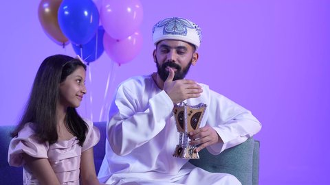 مفهوم التطيب بالبخور ، تجمع العائلة العمانية لاستقبال العيد المبارك, إظهار مشاعر الفرح والسعادة بقدوم العيد، تصوير لعائلة عربية خليجية عمانية تجلس في غرفة المعيشة بايماءات السعادة ، مفهوم الحنان والمحبة والمودة