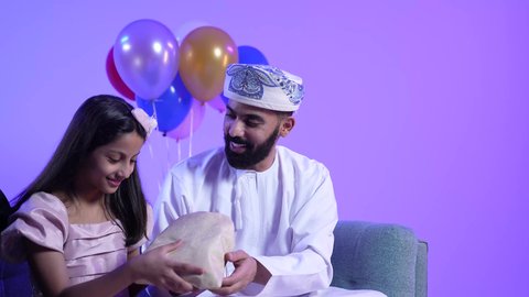 مشاركة وتقديم الهدايا بالمناسبات وأعياد الميلاد, الألفة والمودة بين أفراد الأسرة العمانية، الاجتماعات والاحتفالات العائلية، تصوير لعائلة عربية خليجية عمانية تحتفل بالعيد المبارك ، ايماءات الرضا والسرور