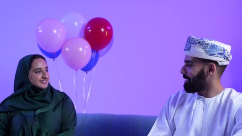 الزينة والبلالين والاحتفالات، تجمع العائلة العمانية لاستقبال العيد المبارك, إظهار مشاعر الفرح والسعادة بقدوم العيد، تصوير لعائلة عربية خليجية عمانية تجلس في غرفة المعيشة بايماءات السعادة ، تبادل المعايدات والتهاني , مفهوم الحنان والمحبة والمودة