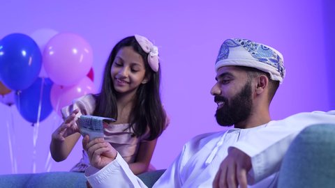 ارتداء الأزياء العمانية التقليدية، المعايدات والتهنئات وطقوس المناسبات الاسلامية في سلطنة عمان، تقديم العيديات للاطفال فى العيد ، تصوير لعائلة عربية خليجية عمانية تحتفل بالعيد المبارك، جو البهجة والفرح والزينة