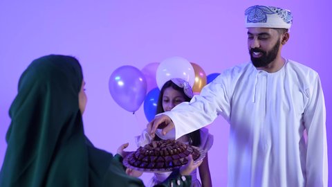 Ramadan decorations and ornaments, celebrating the arrival of Eid, offering hospitality and Eid sweets, showing feelings of affection and family love, a picture of an Arab Gulf Omani family celebrating Islamic holidays, offering hospitality on Eid