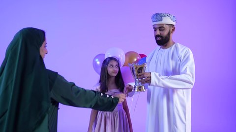 Celebrating the arrival of Eid, offering hospitality and Eid sweets, Ramadan decorations and ornaments, showing feelings of affection and family love, a picture of an Arab Gulf Omani family celebrating Islamic holidays, offering hospitality on Eid