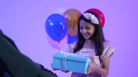 الألفة والمودة بين أفراد الأسرة العمانية، الاجتماعات والاحتفالات العائلية، مشاركة وتقديم الهدايا بالمناسبات وأعياد الميلاد, تصوير لسيدة عربية خليجية عمانية ترتدي العباءه والحجاب ، تقدم الهدية لابنتها بايماءات الرضا والسرور