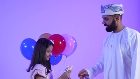 تقديم العيديات للاطفال فى العيد ، المعايدات والتهنئات وطقوس المناسبات الاسلامية في سلطنة عمان، ارتداء الأزياء العمانية التقليدية، تصوير لعائلة عربية خليجية عمانية تحتفل بالعيد المبارك، جو البهجة والفرح والزينة
