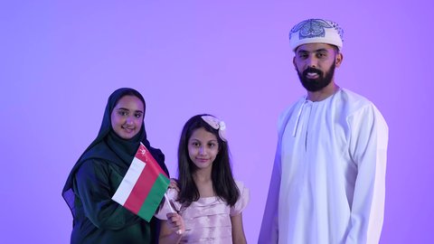 Pride and honor in the symbols and the Omani flag, a picture of an Arab Omani Gulf family, wearing traditional Omani dress, the national flags and banners of the Arab countries