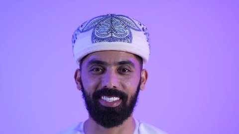 الوقوف باستقامة وثقة بالنفس ، الاهتمام بالاناقة والمظهر الخارجي ،مفهوم الرجولة والقوة، تصوير مقرب لرجل عربي خليجي عماني مبتسم يرتدي الدشداشة والكمة ينظر إلى الكاميرا بإيماءات السرور