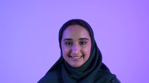 الاهتمام بالموضة والمظهر الخارجي ،مفهوم النعومة والانوثة، تصوير مقرب لسيدة عربية خليجية عمانية مبتسمة ترتدي العباءة والحجاب تنظر إلى الكاميرا بإيماءات السرور، بنت سعودية تقف باستقامة وثقة بالنفس