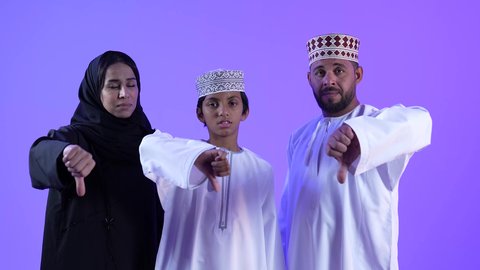 مفهوم التقييم السلبي ، الشعور بالإنزعاج من شيء ما, تصوير لعائلة عربية عمانية خليجية , ترتدي الزي التقليدي العماني , يرفعان اليد بايماءات الرفض والامتناع والانزعاج