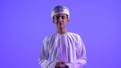 عسر الهضم والشعور بحرقة في المعدة، بورتريه لولد عربي خليجي عماني يرتدي الدشداشة والعمامة يمسك بطنه بإيماءات الألم، الإحساس بالمغص والتعب والإرهاق، الحاجة للمساعدة وزيارة الطبيب، الحاجة للدواء ووضع خطة علاجية، خلفية زرقاء .