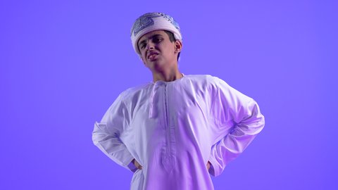 طلب المساعده للذهاب الى المستشفى، التهاب العضلات والفقرات والمفاصل، الإحساس بالتعب والإرهاق, إيماءات الألم في الأكتاف، بورتريه لولد عربي خليجي عماني يرتدي الدشداشة والكمة يضع يدهي على ظهره بتعابير الوجع، الحاجه لوضع خطة علاجية, خلفية زرقاء .
