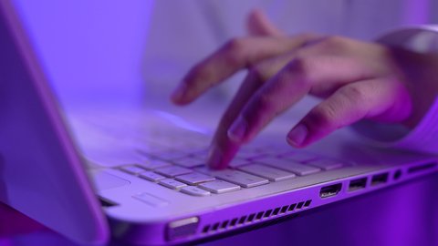 استخدام جهاز تقني حديث، دمج التكنولوجيا في الحياة، تصوير مقرب لولد مراهق عربي خليجي عماني يرتدي الدشداشة والعمامة يقوم بالعمل على الحاسب المحمول بتعابير وايماءات الاندماج والتركيز، خلفية زرقاء