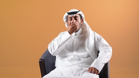 الحاجه للراحه من التعب والإرهاق , شاب سعودي يشعر بألم في العمود الفقري , بورتريه من الجانب لرجل عربي خليجي بحريني يرتدي الثوب التقليدي والشماغ ينحني ويضع يده اسفل ظهره بتعابير الشعور بالوجع, طلب المساعده للذهاب الى الطبيب