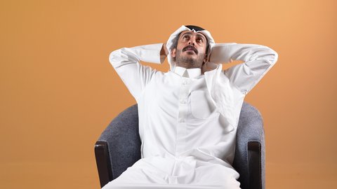 طلب المساعده للذهاب الى الطبيب، الحاجه للراحه من التعب والإرهاق , شاب سعودي يشعر بألم في العمود الفقري , بورتريه من الجانب لرجل عربي خليجي بحريني يرتدي الثوب التقليدي والشماغ ينحني ويضع يده اسفل ظهره بتعابير الشعور بالوجع