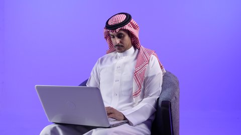 مفهوم التوظيف أونلاين, إجراء مكالمات الفيديو باستخدام الحاسوب المحمول، إقامة اجتماعات العمل عن بعد عبر الانترنت، دمج التقنية بالأعمال الإدارية، تصوير لرجل عربي خليجي بحريني يرتدي الثوب التقليدي والشماغ يجلس على كرسي