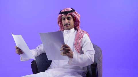 تدوين الملاحظات على الورق، تصوير لرجل عربي خليجي سعودي يرتدي الزي التقليدي  والشماغ ويحمل بيده قلم ومجموعة من الاوراق، التخطيط للعمل، توقيع عقد عمل، تدوين نتائج الاجتماع، اعداد تقارير ومهام العمل، دراسة جدوى الاعمال