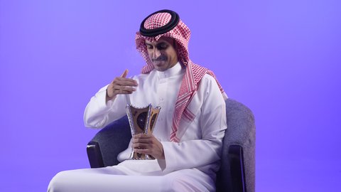 التبخر في الأعياد والمناسبات السعيدة، اتباع العادات والتقاليد العربية الأصيلة، التبخير واستخدام العطور والمطيبات، تصوير لشاب عربي خليجي بحريني يرتدي الثوب التقليدي والشماغ يجلس على كرسي ويمسك بيده المبخرة
