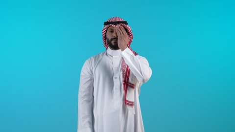 تعابير الخجل والحياء، تذكر شيء ما بشكل مفاجئ، تصوير لرجل عربي خليجي بحريني يرتدي الثوب التقليدي والشماغ يغطي عينيه بيده بايماءات السعادة، الشعور بالفرح والسرور