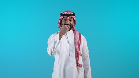 الانجاز وتحقيق الاهداف، تصويرلرجل عربي خليجي بحريني مبتسم يرتدي الثوب التقليدي والشماغ  يرفع قبضة يديه للاعلى بإيماءات الفوز والانتصار والنجاح, شاب سعودي ينظر الى الكاميرا بتعابير السعادة والقوة والسرور