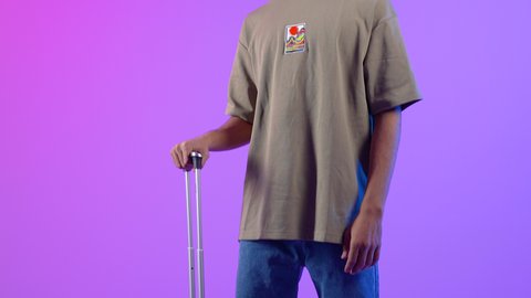 مفهوم السياحة و السفر، الاستعداد و تجهيز الأمتعة للسفر في جولة سياحية، بورتريه لرجل سعودي  يمسك حقيبة سفر سوداء، شاب عربي عمانى خليجي يرتدي الزي الكاجوال ينظر الى الكاميرا, ايماءات وجه تدل على الحماس للقيام برحلة سياحية، خلفية ملونه