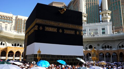 The Qiblah of Islam and Muslims, performing the Hajj and Umrah rituals, the destination of Muslims from all over the world, a sacred Islamic religious place and landmark in Saudi Arabia, the concept of worship and drawing closer to God, pilgrims and Umrah performers circumambulating the Kaaba in Mecca, the Kingdom Tower and the hotel towers overlooking the Haram