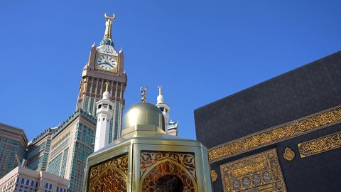 The Qiblah of Islam and Muslims, performing the Hajj and Umrah rituals, the destination of Muslims from all over the world, a sacred Islamic religious place and landmark in Saudi Arabia, the concept of worship and drawing closer to God, pilgrims and Umrah performers circumambulating the Kaaba in Mecca, the Kingdom Tower and the hotel towers overlooking the Haram