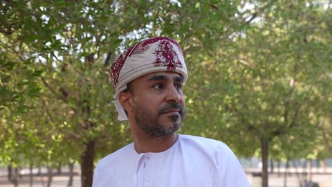 الاستجمام بالطبيعة واستنشاق الهواء الطلق، الاستمتاع بالأجواء في إحدى المنتزهات، الخروج إلى أحد الاماكن العامة للترفيه عن النفس، رجل عربي خليجي عماني يرتدي الزي العماني يسير فى احدي حدائق سلطنة عمان