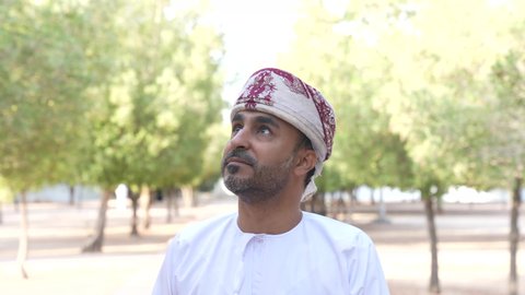 الخروج إلى أحد الاماكن العامة للترفيه عن النفس،  الاستجمام بالطبيعة واستنشاق الهواء الطلق،الاستمتاع بالأجواء في إحدى المنتزهات، رجل عربي خليجي عماني يرتدي الزي العماني يسير فى احدي حدائق سلطنة عمان