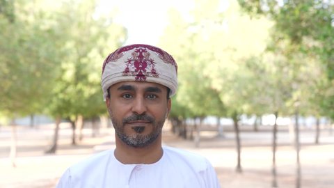 الاستجمام بالطبيعة واستنشاق الهواء الطلق، الخروج إلى أحد الاماكن العامة للترفيه عن النفس، الاستمتاع بالأجواء في إحدى المنتزهات، رجل عربي خليجي عماني يرتدي الزي العماني يسير فى احدي حدائق سلطنة عمان