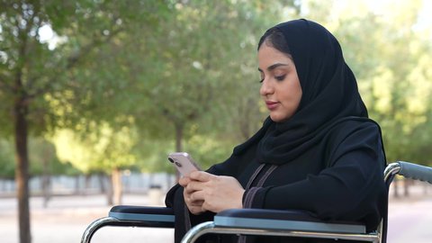 الاطمئنان على الاهل والاصدقاء عبر الجوال، التجول والتنزه فى الهواء الطلق، توفير اجهزة ومعدات تساعد بالحركة والتنقل ، العنايه بأصحاب الهمم وتأمين احتياجاتهم الخاصة، تصوير لسيدة عربية خليجية عمانية مقعده ترتدي العباءه و الحجاب تجلس على كرسي متحرك