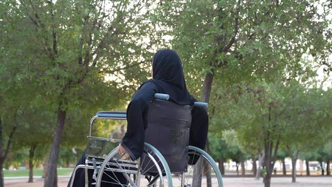 الاستجمام بالطبيعة واستنشاق الهواء الطلق، شعور المعاقين بالإنتماء والتقدير والإحترام في سلطنة عمان ،  العنايه بأصحاب الهمم وتأمين احتياجاتهم الخاصة، توفير اجهزة ومعدات تساعد بالحركة والتنقل،تصوير لإمرأة مريضة عربية عمانية خليجية ترتدي الحجاب والعباءة تجلس على كرسي متحرك،  الاستمتاع بالأجواء في إحدى المنتزهات