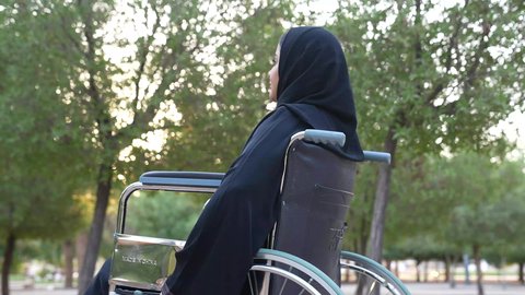 شعور المعاقين بالإنتماء والتقدير والإحترام في سلطنة عمان ،  العنايه بأصحاب الهمم وتأمين احتياجاتهم الخاصة، توفير اجهزة ومعدات تساعد بالحركة والتنقل،تصوير لإمرأة مريضة عربية عمانية خليجية ترتدي الحجاب والعباءة تجلس على كرسي متحرك،  الاستمتاع بالأجواء في إحدى المنتزهات، الاستجمام بالطبيعة واستنشاق الهواء الطلق