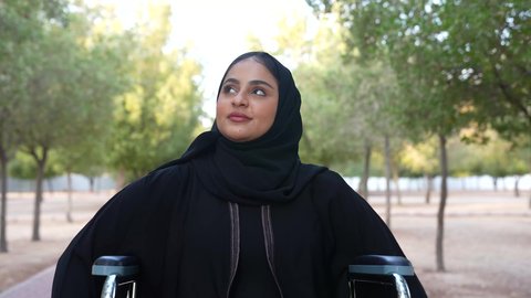 العنايه بأصحاب الهمم وتأمين احتياجاتهم الخاصة، توفير اجهزة ومعدات تساعد بالحركة والتنقل،تصوير لإمرأة مريضة عربية عمانية خليجية ترتدي الحجاب والعباءة تجلس على كرسي متحرك، شعور المعاقين بالإنتماء والتقدير والإحترام في سلطنة عمان ،  الاستمتاع بالأجواء في إحدى المنتزهات، الاستجمام بالطبيعة واستنشاق الهواء الطلق