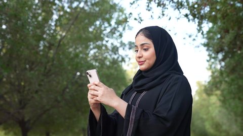 الاستجمام بالطبيعة واستنشاق الهواء الطلق، دمج التكنولوجيا الحديثه فى الحياه اليوميه  ،تصوير من الخلف لسيدة عربية خليجية عمانية ترتدي الزي العماني تسير فى احدي حدائق سلطنة عمان ، اجراء المكالمات الهاتفية  ،شابه سعوديه تخرج إلى أحد الاماكن العامة للترفيه عن النفس