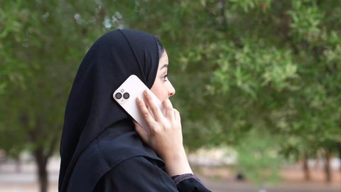 الاستجمام بالطبيعة واستنشاق الهواء الطلق، دمج التكنولوجيا الحديثه فى الحياه اليوميه  ، اجراء المكالمات الهاتفية  ،شابه سعوديه تخرج إلى أحد الاماكن العامة للترفيه عن النفس ، تصوير من الخلف لسيدة عربية خليجية عمانية ترتدي الزي العماني تسير فى احدي حدائق سلطنة عمان