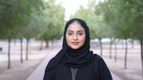 Recreation in nature and fresh air, enjoying the atmosphere in a park, a photograph of an Omani Gulf Arab woman wearing Omani clothing walking in one of the parks of the Sultanate of Oman, a young Saudi woman going out to a public place for entertainment.