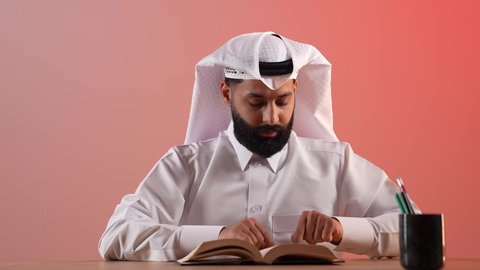 تنمية المهارات وتوسيع المعارف والأفكار، الاستمتاع بقراءة الكتب والقصص والروايات، بورتريه لرجل عربي خليجي قطري يرتدي الثوب التقليدي والغترة يجلس خلف طاولة المكتب ويمسك بيديه كتاب، زيادة الذخيرة الفكرية، قضاء أوقات الفراغ بشكل مفيد، خلفية ملونة