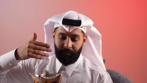 اتباع العادات والتقاليد العربية الأصيلة، استخدام خشب العود  في الأعياد والمناسبات السعيدة، شاب سعودي يقوم بالتبخير واستعمال العطور والمطيبات، بورتريه مقرب لرجل عربي خليجي قطري يرتدي الثوب والغترة يجلس على كرسي ويمسك بيده المبخرة بايماءات الفرح، خلفية ملونة